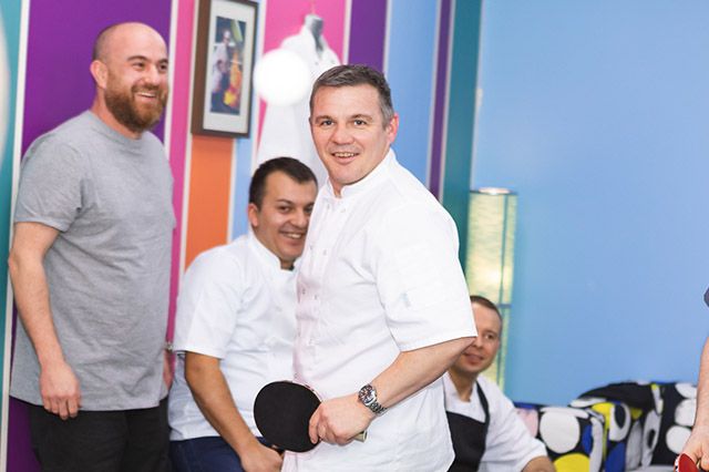 Chefs playing ping pong in a well decorated room
