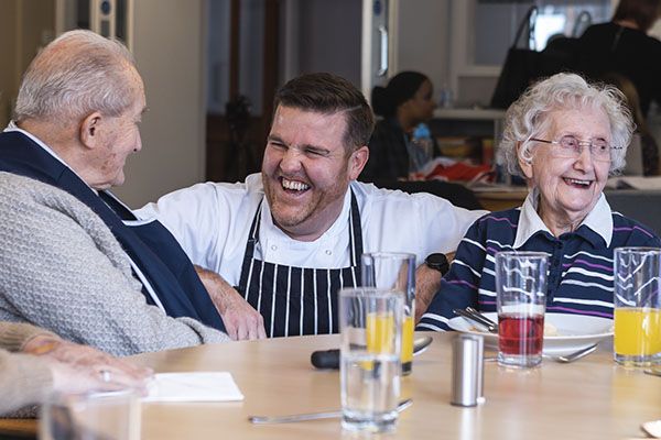 A care home chef joking with 2 of the residents